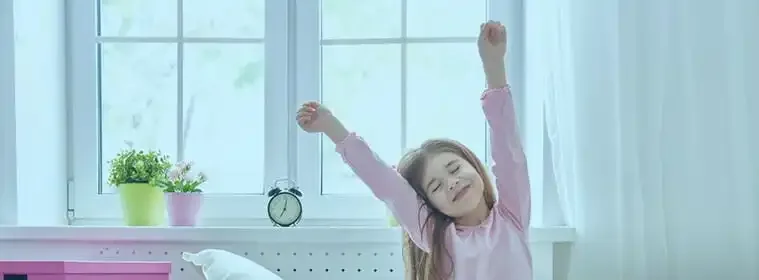 Child stretching in a bright bedroom lit by a UPVC window