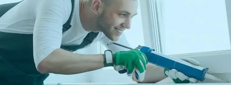 Installer applying sealant around a newly fitted UPVC window frame