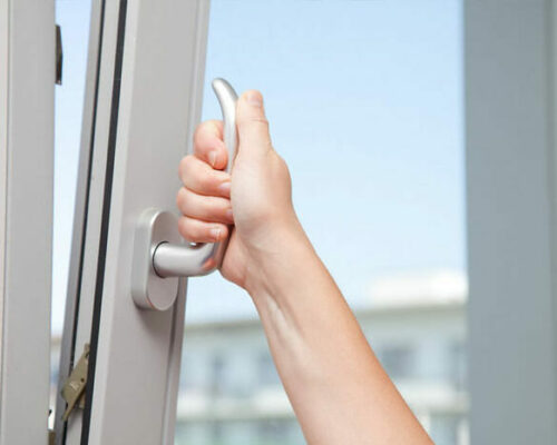 Hand turning the handle of a UPVC tilt window